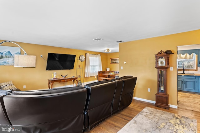 living room featuring visible vents, baseboards, and wood finished floors