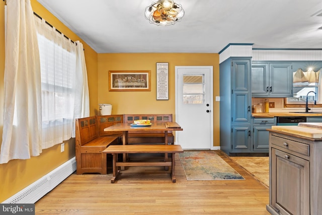 dining room with a baseboard heating unit, light wood-style flooring, plenty of natural light, and baseboards