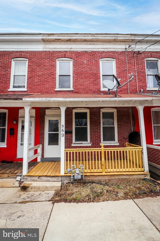 townhome / multi-family property with brick siding and covered porch