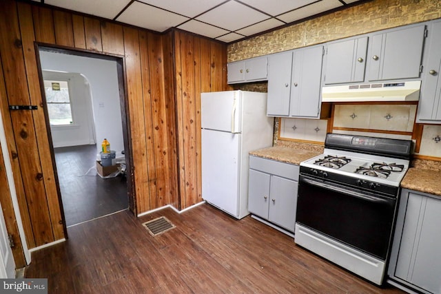 kitchen with white appliances, visible vents, dark wood-type flooring, light countertops, and under cabinet range hood