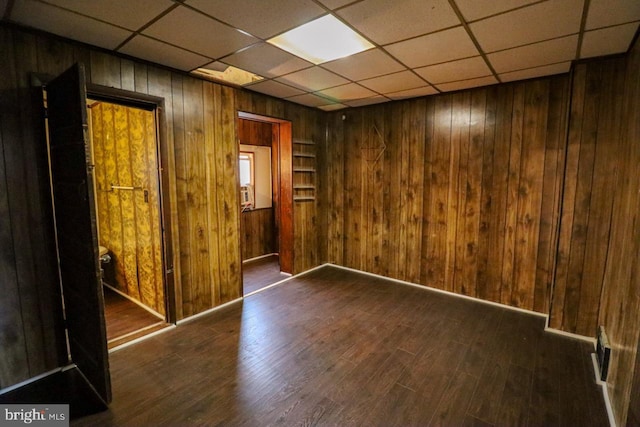 unfurnished room featuring wood walls, a paneled ceiling, and wood finished floors