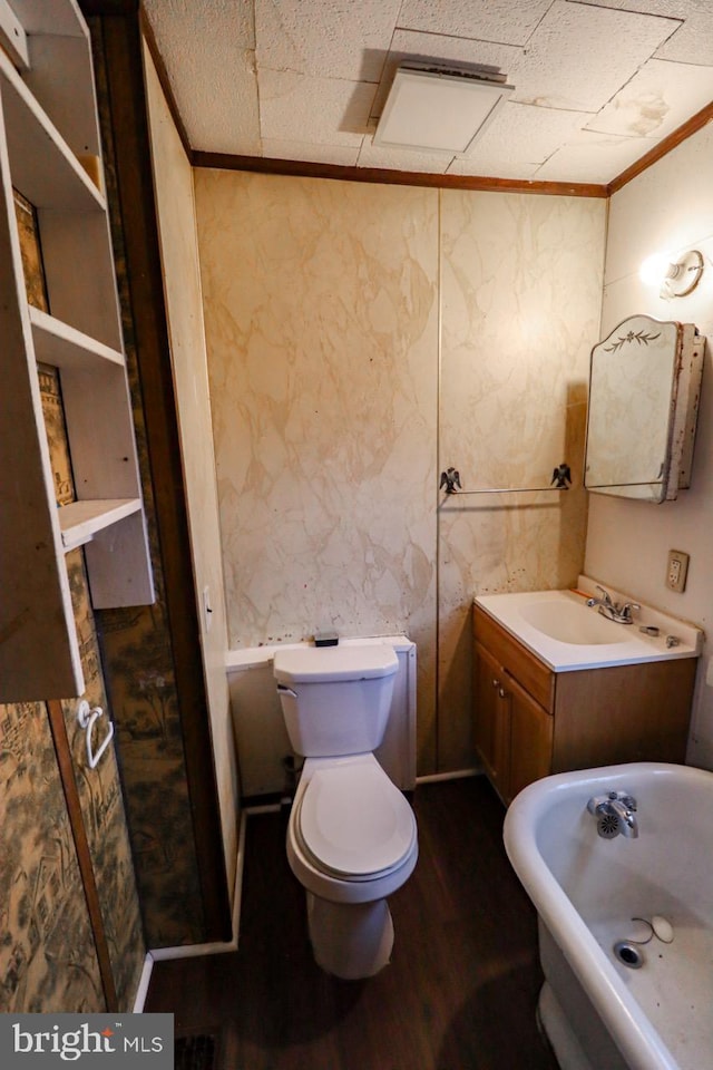 bathroom featuring vanity, wood finished floors, ornamental molding, toilet, and a washtub