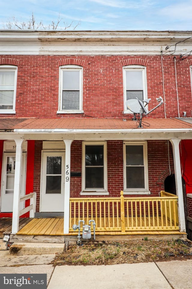 view of property with a porch and brick siding