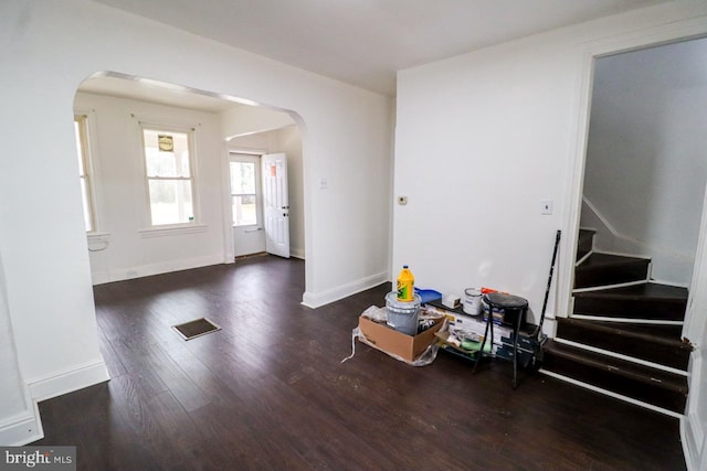 foyer entrance with visible vents, baseboards, stairway, wood finished floors, and arched walkways