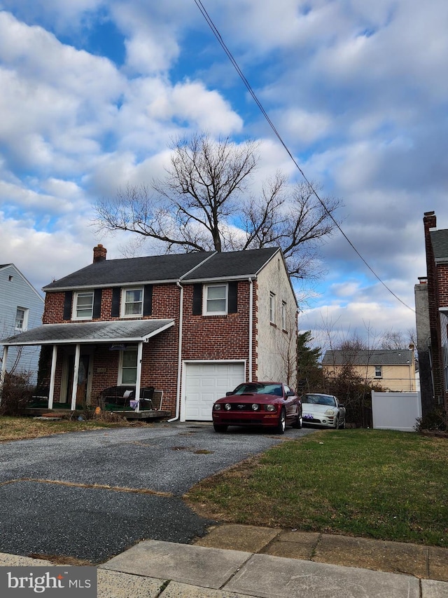 view of side of home featuring brick siding, a porch, a lawn, a garage, and driveway