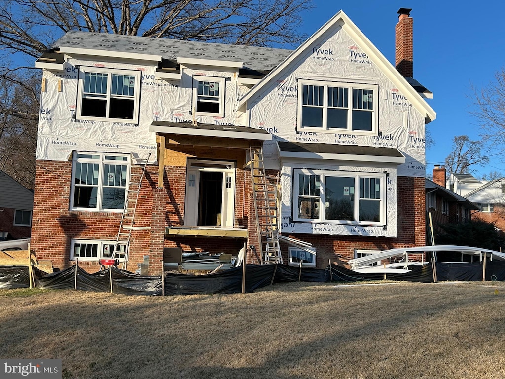 view of front of house with a front yard, brick siding, and a chimney