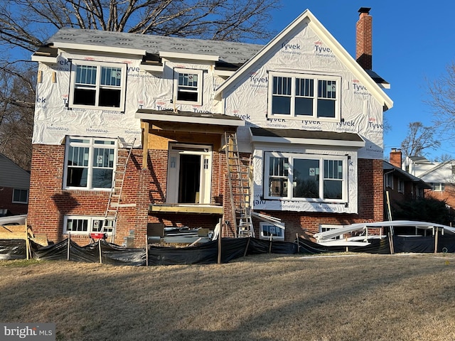 view of front of house with a front yard, brick siding, and a chimney