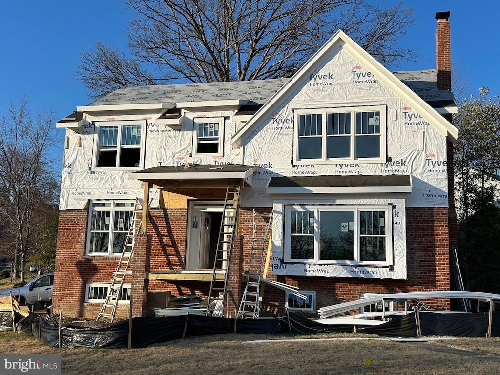 view of front of house featuring brick siding and a chimney