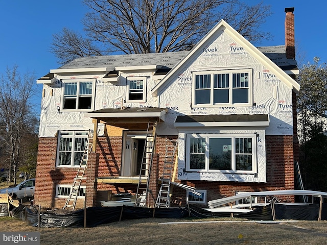 view of front of house featuring brick siding and a chimney