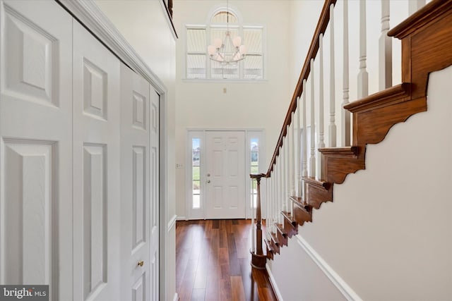 entrance foyer featuring dark wood-style flooring, baseboards, an inviting chandelier, a high ceiling, and stairway