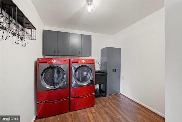 washroom with baseboards, wood finished floors, washer and dryer, and cabinet space