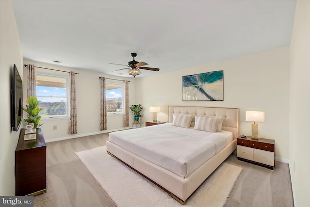 bedroom featuring light colored carpet, baseboards, and a ceiling fan