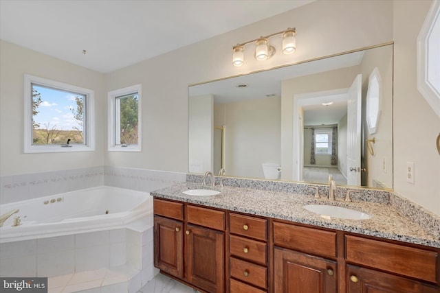 full bath with a bath, toilet, a sink, and double vanity