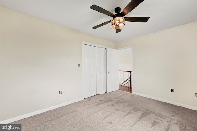 unfurnished bedroom with carpet floors, a closet, a ceiling fan, and baseboards