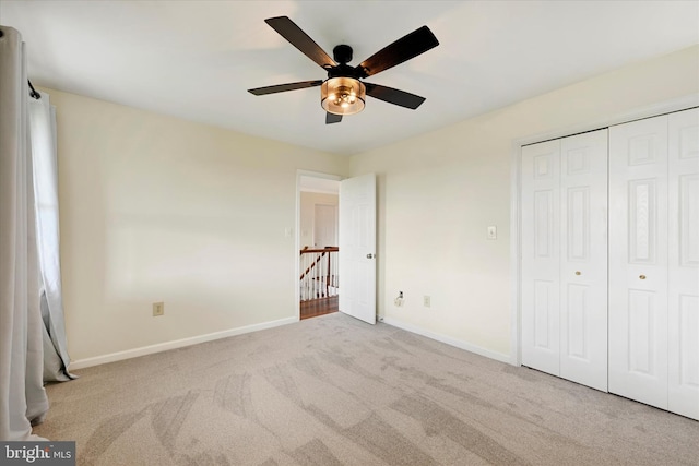 unfurnished bedroom with carpet floors, a closet, baseboards, and ceiling fan