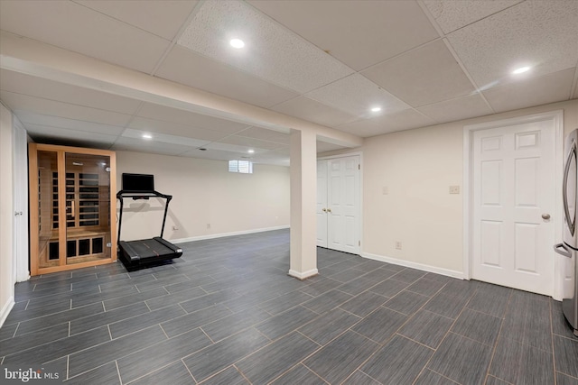 finished basement with recessed lighting, freestanding refrigerator, a drop ceiling, and baseboards