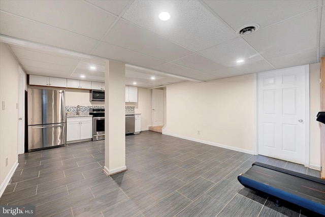 interior space featuring recessed lighting, freestanding refrigerator, a paneled ceiling, and baseboards