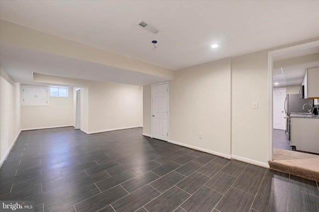 below grade area featuring recessed lighting, wood tiled floor, visible vents, a sink, and baseboards
