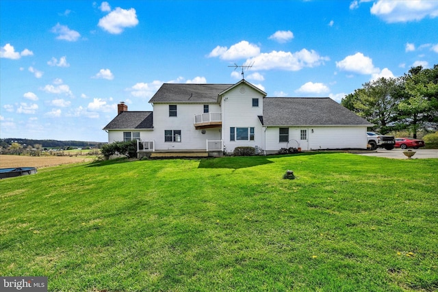 back of property featuring a lawn, a chimney, and a balcony