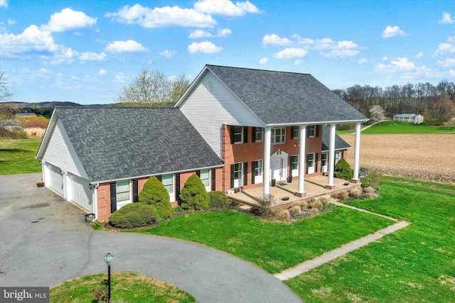 exterior space featuring a front lawn, driveway, a porch, a garage, and brick siding