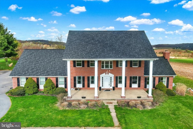 view of front of property with brick siding, roof with shingles, and a front yard