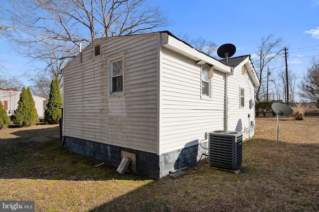 view of side of property with a lawn and cooling unit