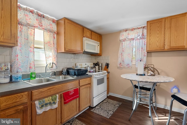 kitchen featuring dark wood-type flooring, a sink, backsplash, white appliances, and baseboards