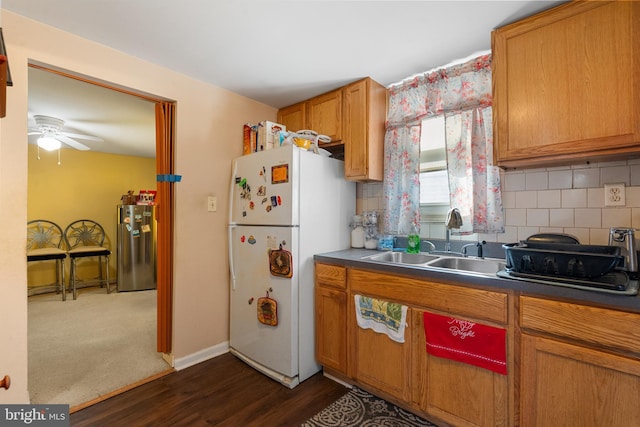 kitchen with a sink, brown cabinets, backsplash, and freestanding refrigerator