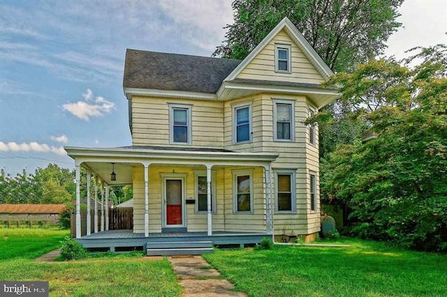 victorian-style house with a shingled roof, covered porch, and a front lawn