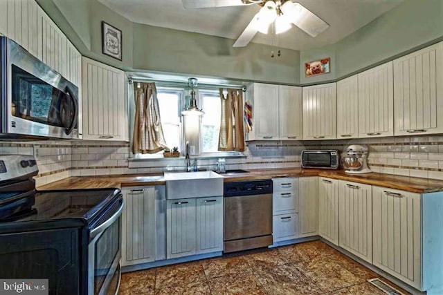 kitchen featuring stainless steel appliances, butcher block counters, visible vents, backsplash, and a sink