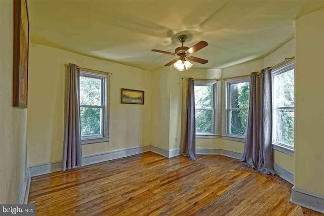 spare room with a ceiling fan, baseboards, and wood finished floors