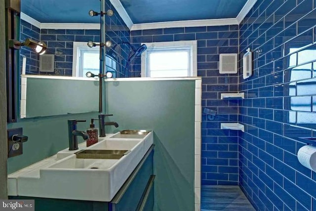 bathroom with ornamental molding, a tile shower, and vanity