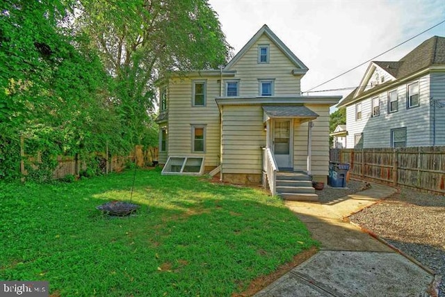 back of house with entry steps, fence private yard, and a yard