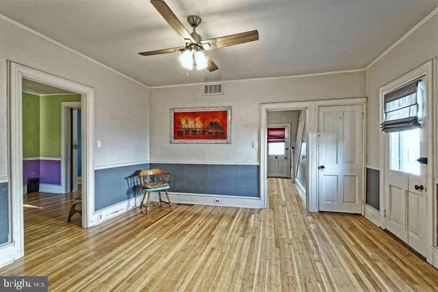 empty room featuring crown molding, visible vents, ceiling fan, wood finished floors, and baseboards