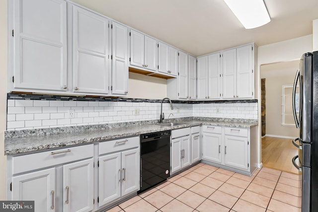 kitchen featuring light tile patterned flooring, freestanding refrigerator, a sink, dishwasher, and backsplash