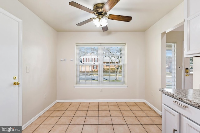 unfurnished dining area featuring light tile patterned flooring, baseboards, and ceiling fan