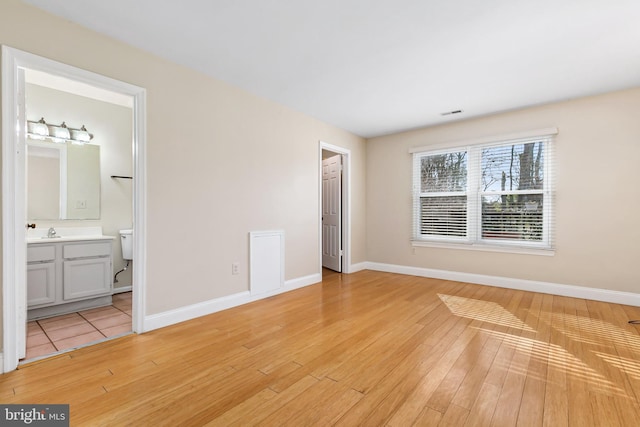 unfurnished bedroom featuring a sink, baseboards, and light wood finished floors