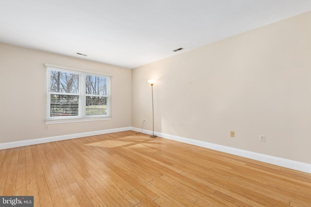 unfurnished room with visible vents, light wood-style flooring, and baseboards