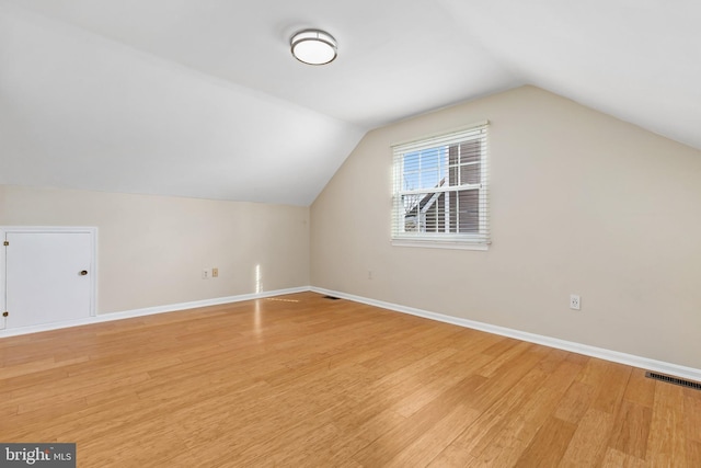 additional living space with lofted ceiling, light wood-style floors, baseboards, and visible vents