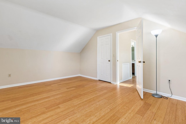 bonus room featuring light wood-style flooring, lofted ceiling, and baseboards