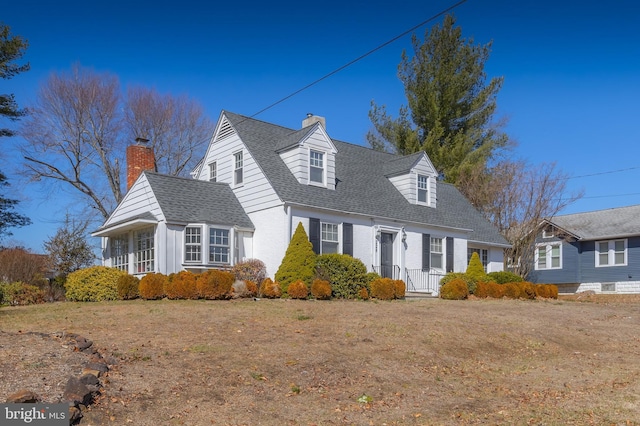 cape cod home with a front lawn, a chimney, and roof with shingles