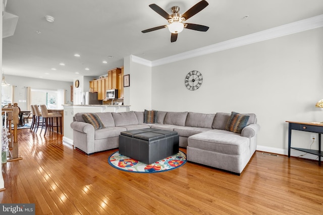 living area featuring visible vents, baseboards, recessed lighting, ornamental molding, and light wood-style floors