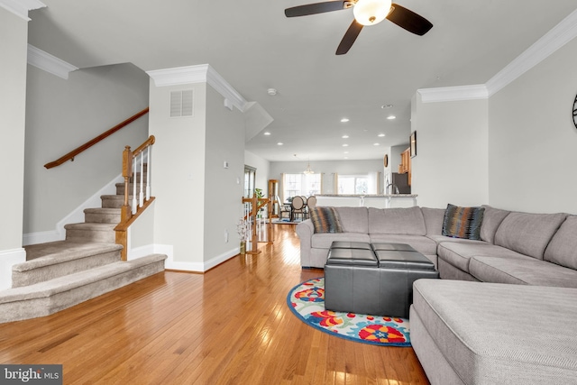 living room with visible vents, light wood-style floors, crown molding, baseboards, and stairs