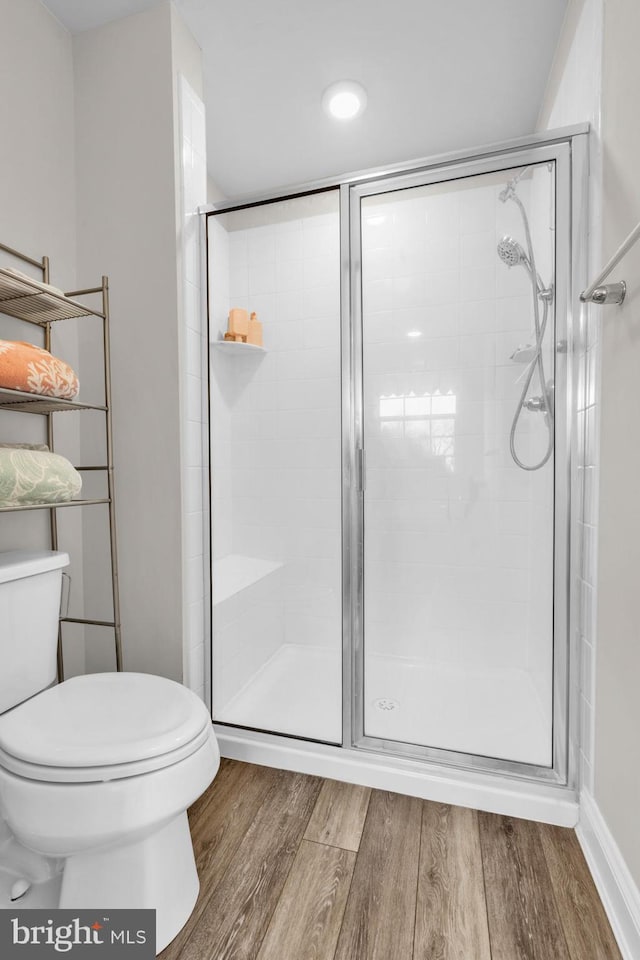 bathroom featuring a stall shower, toilet, and wood finished floors