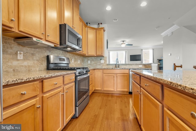 kitchen featuring ornamental molding, a sink, backsplash, stainless steel appliances, and light wood-style floors