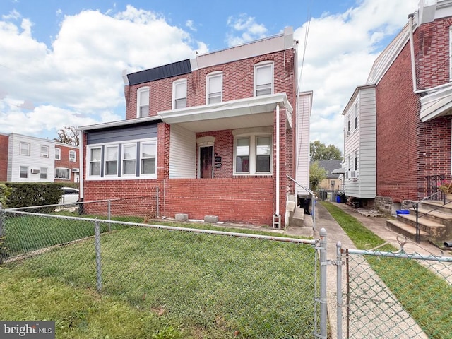 multi unit property with fence private yard, a gate, brick siding, and a front lawn