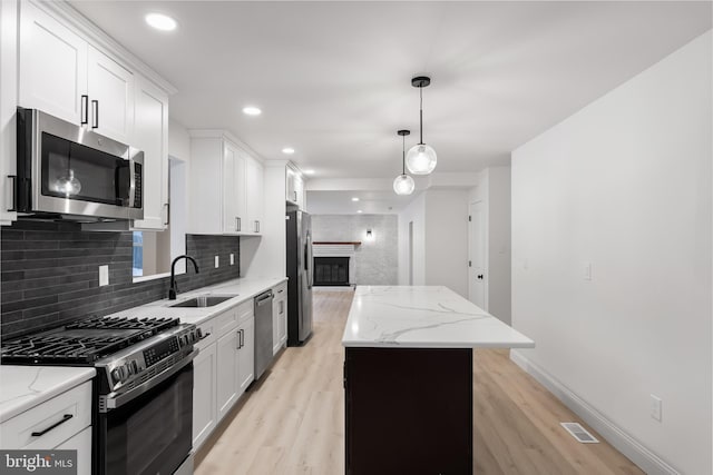 kitchen featuring a sink, visible vents, appliances with stainless steel finishes, a center island, and tasteful backsplash