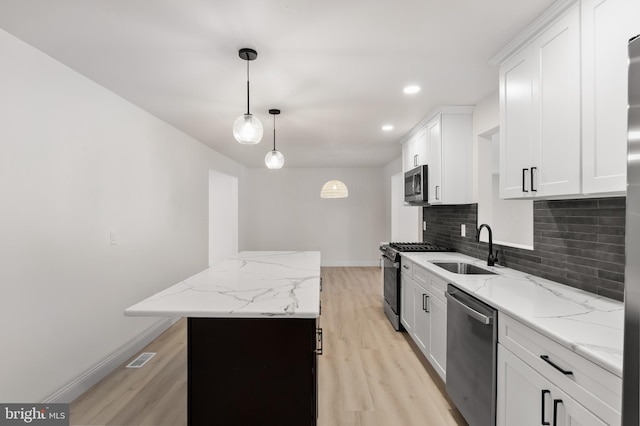 kitchen with a sink, baseboards, appliances with stainless steel finishes, light wood-type flooring, and decorative backsplash