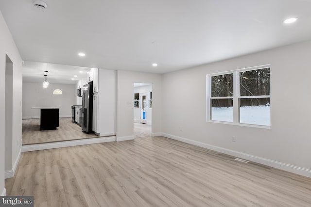 unfurnished living room featuring baseboards, visible vents, light wood-style flooring, and recessed lighting