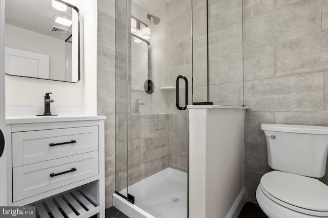 full bath with tile walls, visible vents, toilet, a stall shower, and vanity